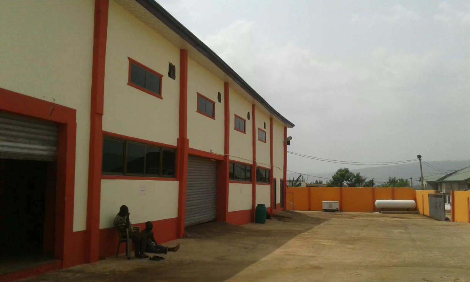 Exterior of the cream-and-orange Oyarifa warehouse building with roller doors