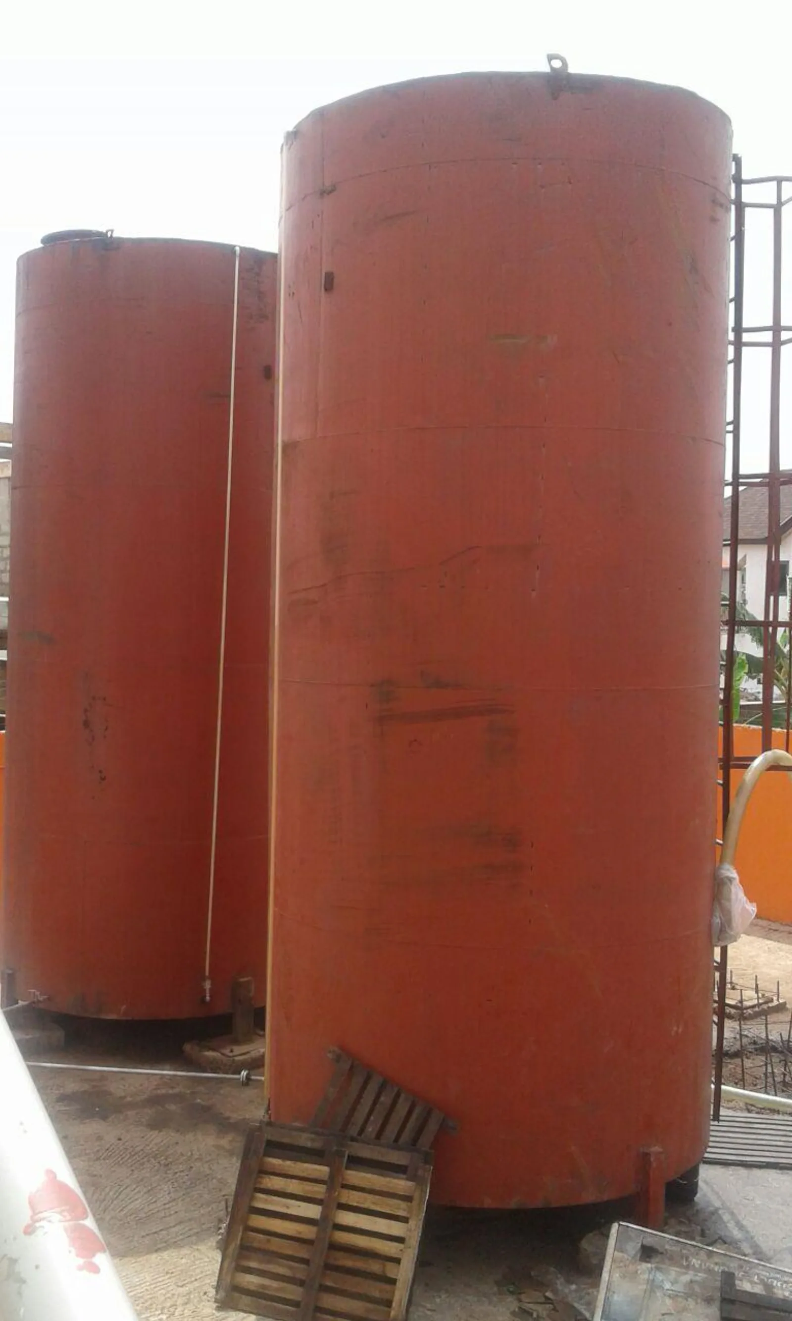Two large orange oil storage tanks in the Oyarifa factory yard